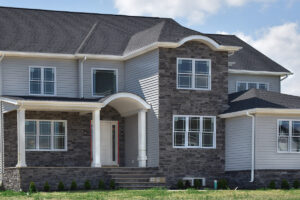 Large two story house with grey siding and veneer stone accent walls