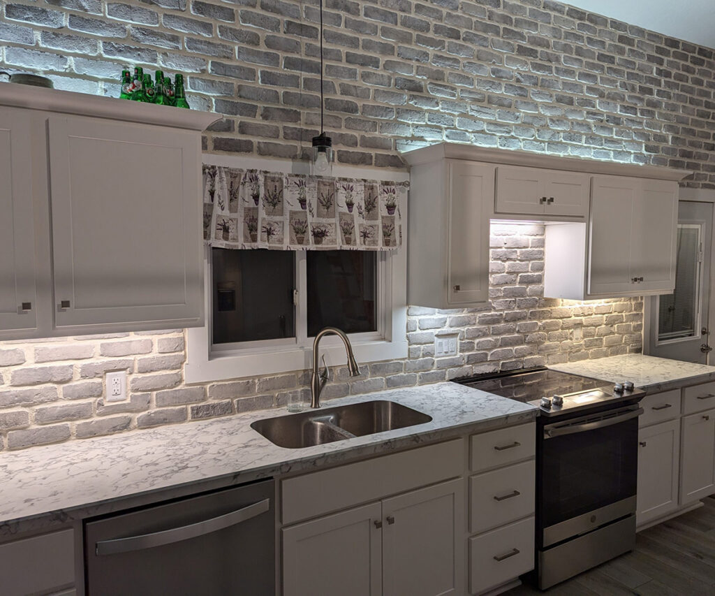 A modern kitchen with the best kitchen backsplash, white brick veneer and undercabinet lighting.