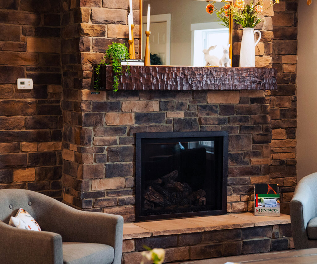 Stone veneer fireplace with rustic wood mantel in a cozy living room.