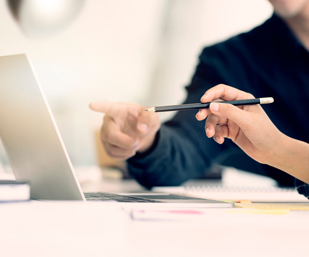 Person pointing at laptop while holding pencil during home design planning.