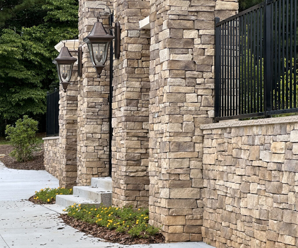 Exterior stone veneer columns and wall along walkway with decorative lantern lights.
