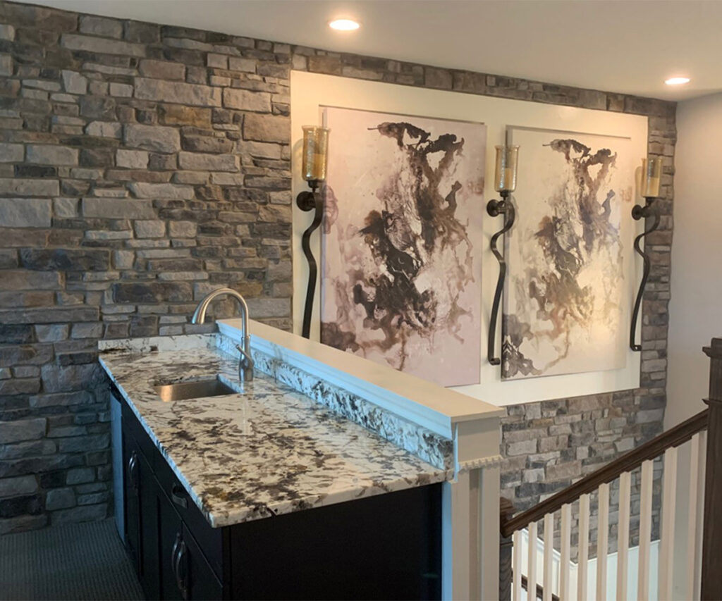 Stone accent wall with cream artwork and granite counter in a modern home interior.