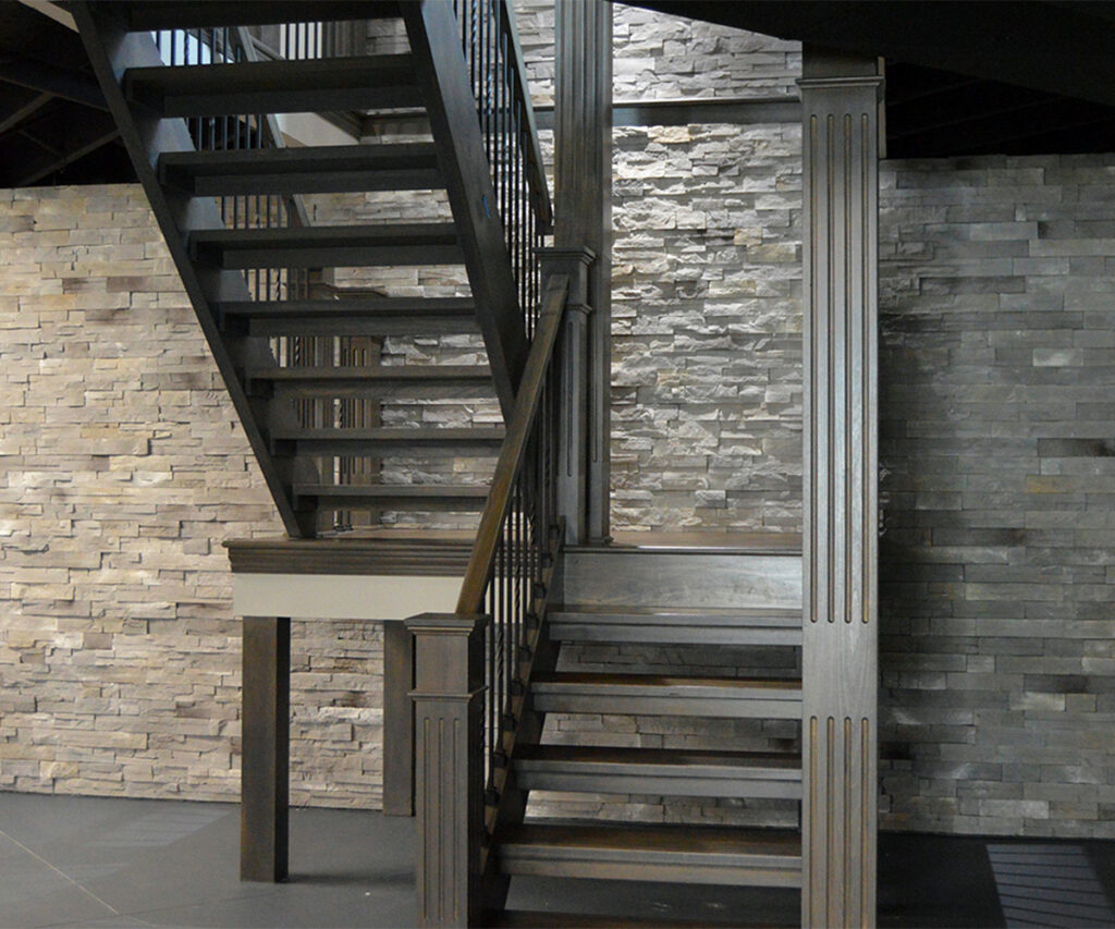 Interior stone wall blending gray and cream tones beside a modern staircase.